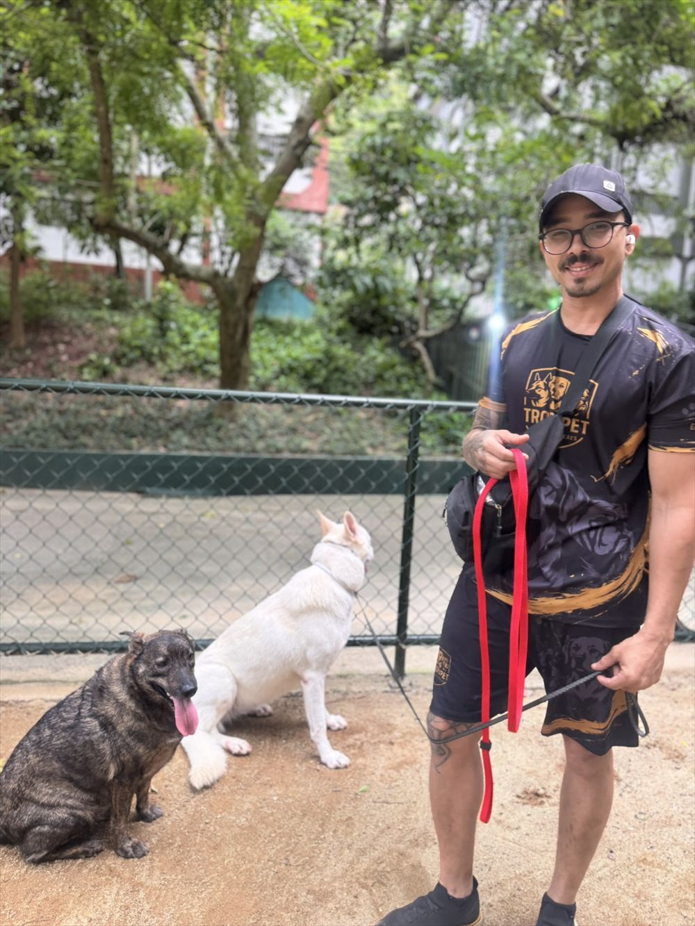 Jordan sorrindo no parcão com dois cães na guia