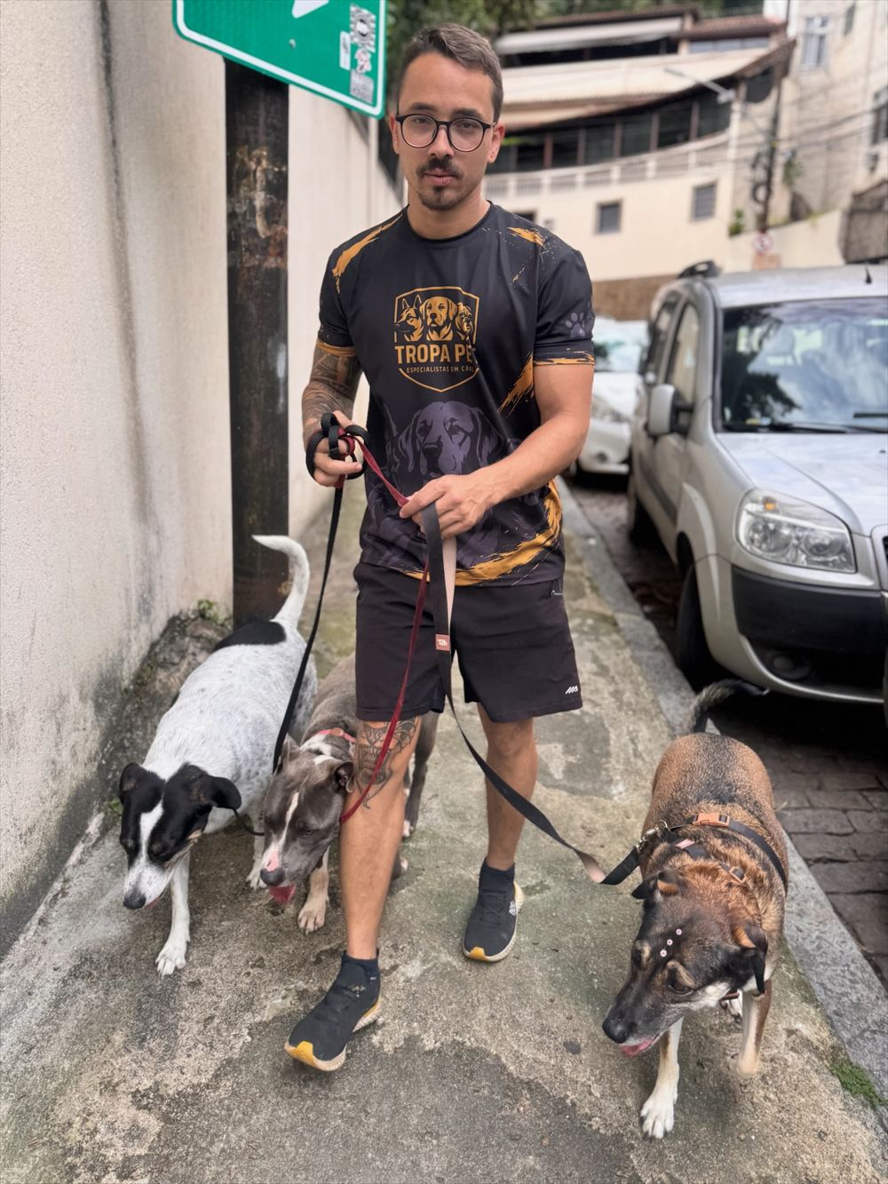 Jordan com três cães na calçada, em passeio matilha